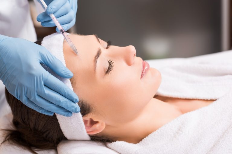 beautician making injection to woman on face at beauty salon